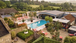 A backyard with a swimming pool, lounge chairs, and a covered patio area.