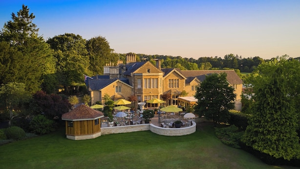 A large, historic house with a spacious patio area featuring outdoor furniture and umbrellas.