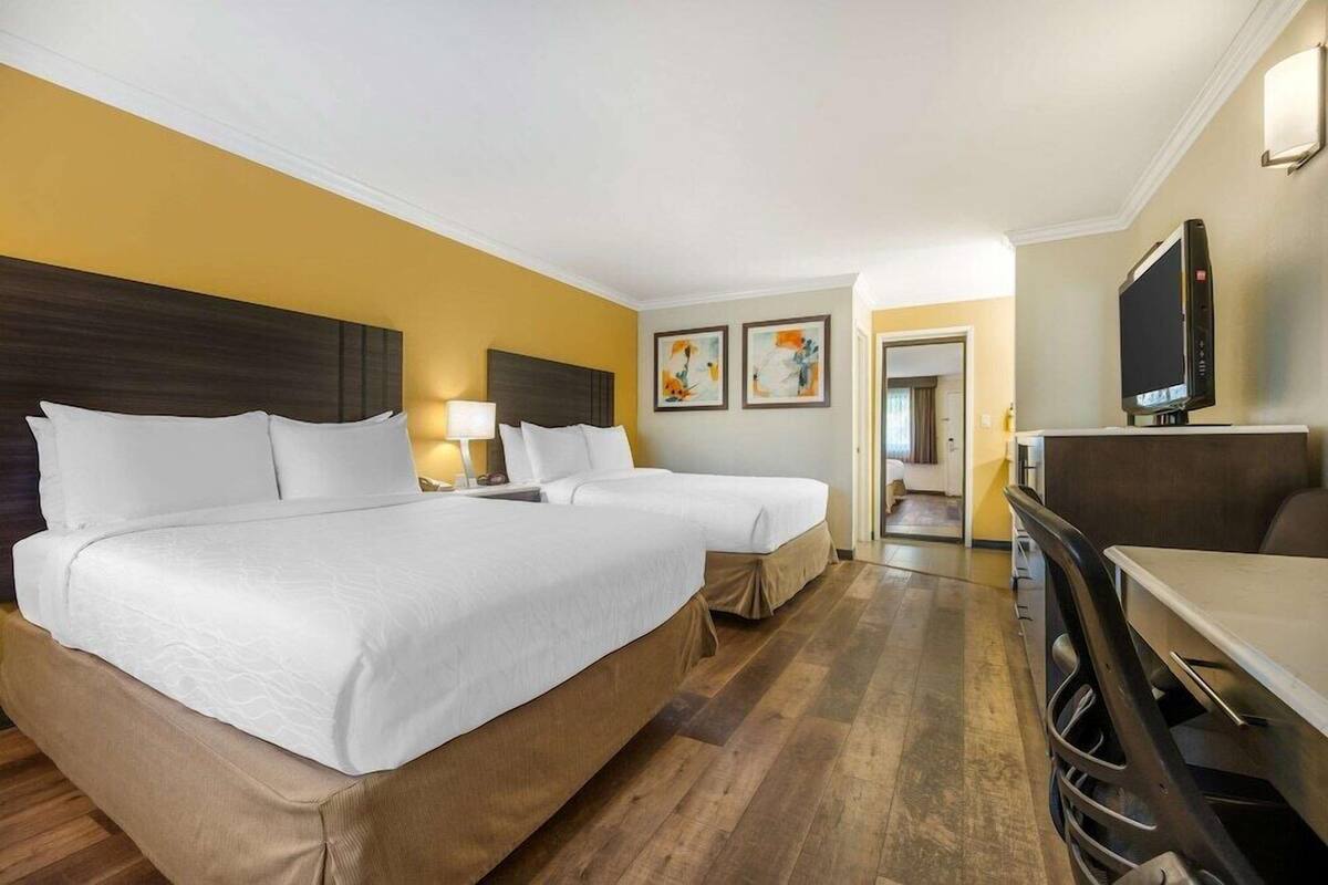 A hotel room with two beds, a TV, a desk, and a chair.