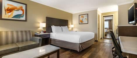 A hotel room with a bed, a sofa, a desk, and a TV.