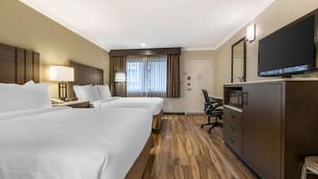 Habitación de hotel con dos camas, un escritorio con lámpara, televisor, microondas y armario.