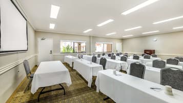Una sala conferenze con diversi tavoli, sedie e uno schermo per proiezioni.