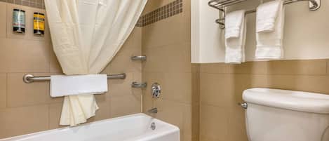 Une salle de bain équipée d’une baignoire, de toilettes, d’un porte-serviettes et d’un rideau de douche.