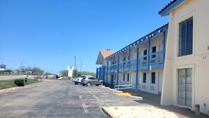 Un motel composé d’un bâtiment à deux étages, d’un espace de stationnement couvert et surplombé d’un ciel d’un bleu éclatant.