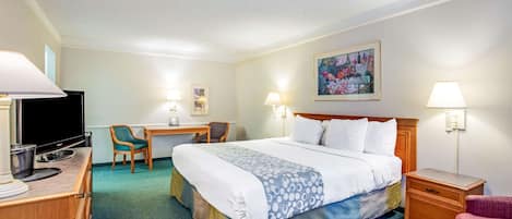 A hotel room with a bed, desk, chair, TV, and lamps.
