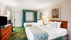 Une chambre d’hôtel avec deux lits, une télévision, une commode et un tableau au mur.