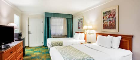 Habitación de hotel con dos camas, televisión, cómoda y un cuadro en la pared.