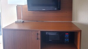 Un meuble en bois sur lequel est fixé un téléviseur à écran plat, avec une petite étagère en dessous et un bloc de tiroirs sur le côté droit.