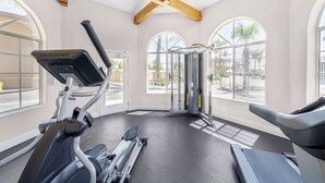 A gym with exercise equipment, large windows, and a view of palm trees. - Best Western Oxnard Inn (Oxnard)