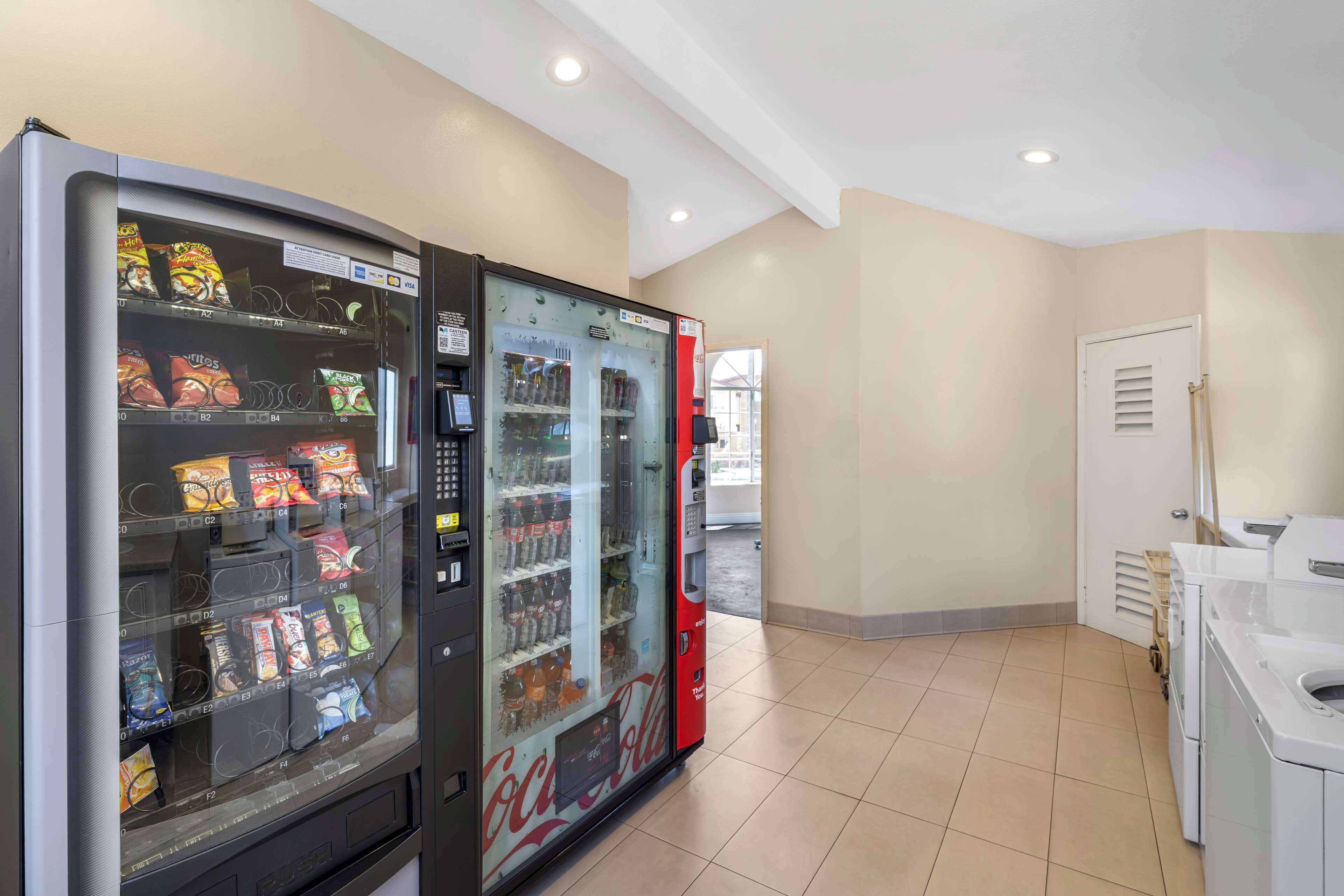 A vending machine with snacks and drinks, a washing machine, and a dryer in a hotel room.