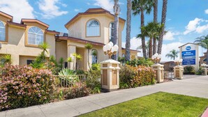A hotel with a modern architectural design, featuring a central courtyard with palm trees and a variety of plants. - Best Western Oxnard Inn (Oxnard)