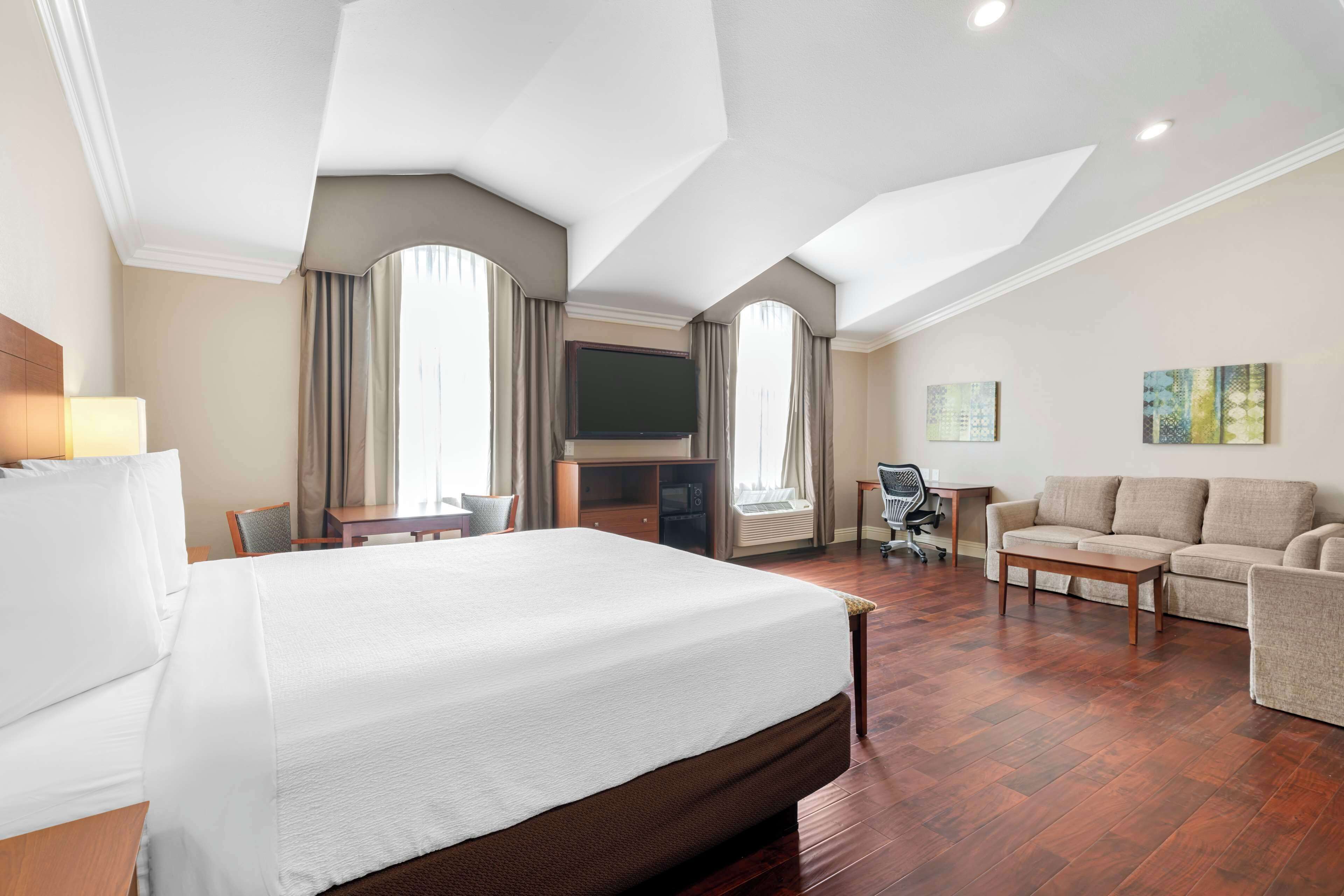 Una habitación de hotel con una cama grande, un sofá, un televisor y un escritorio.