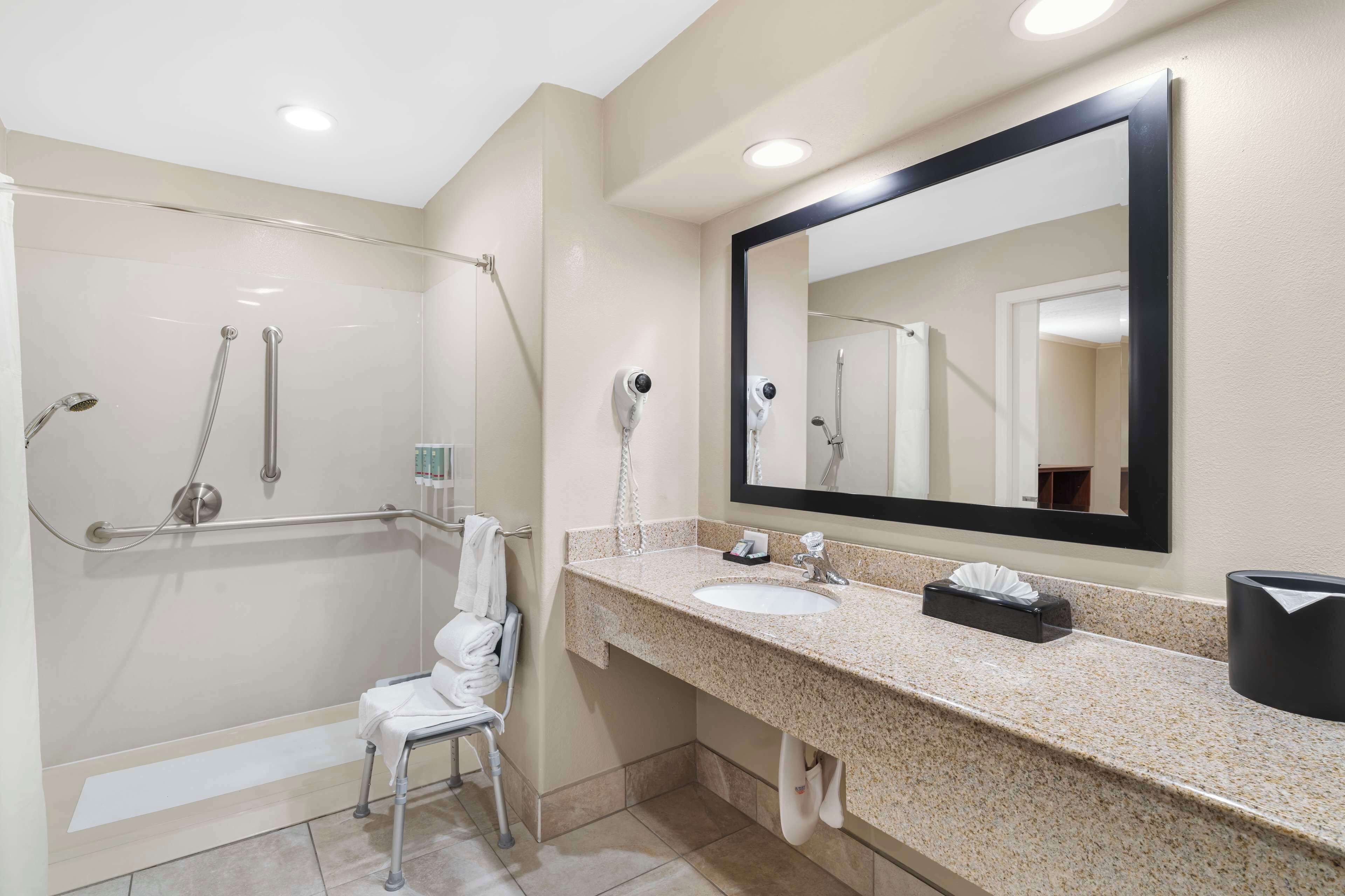 A modern bathroom with a glass-enclosed shower, a sink with a mirror, and a towel rack.
