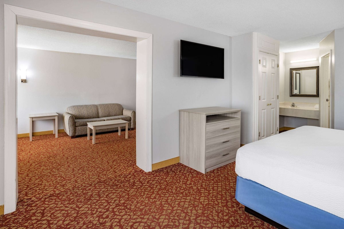 A hotel room with a bed, a TV, a sofa, and a desk.
