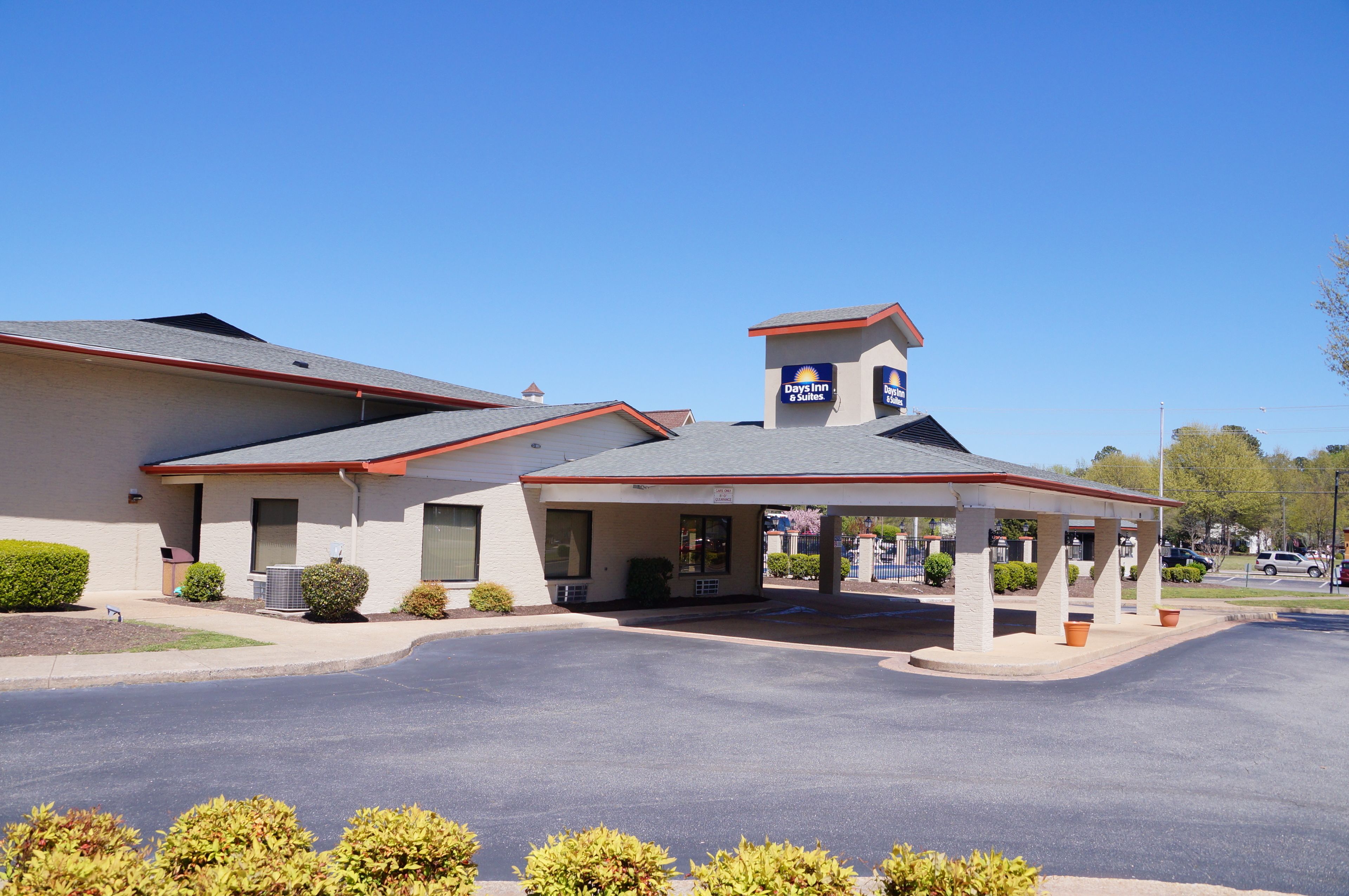 A Days Inn & Suites with a covered parking area and a small tower-like structure on the roof.