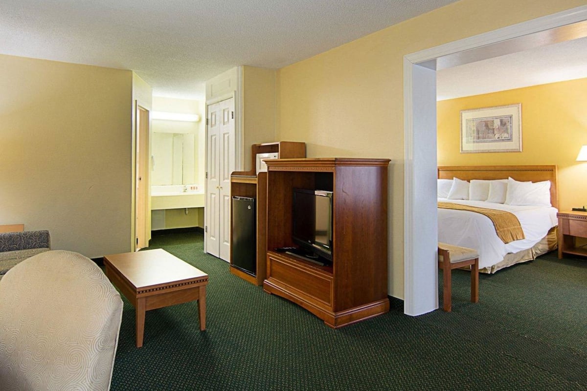 A hotel room with a bed, a desk, a television, and a wardrobe.