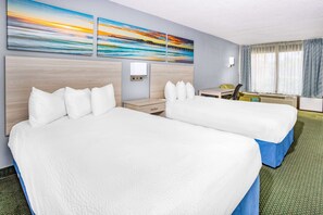 A hotel room with two beds, a desk, a chair, and a window with curtains. - Days Inn & Suites by Wyndham Williamsburg Colonial (Williamsburg)