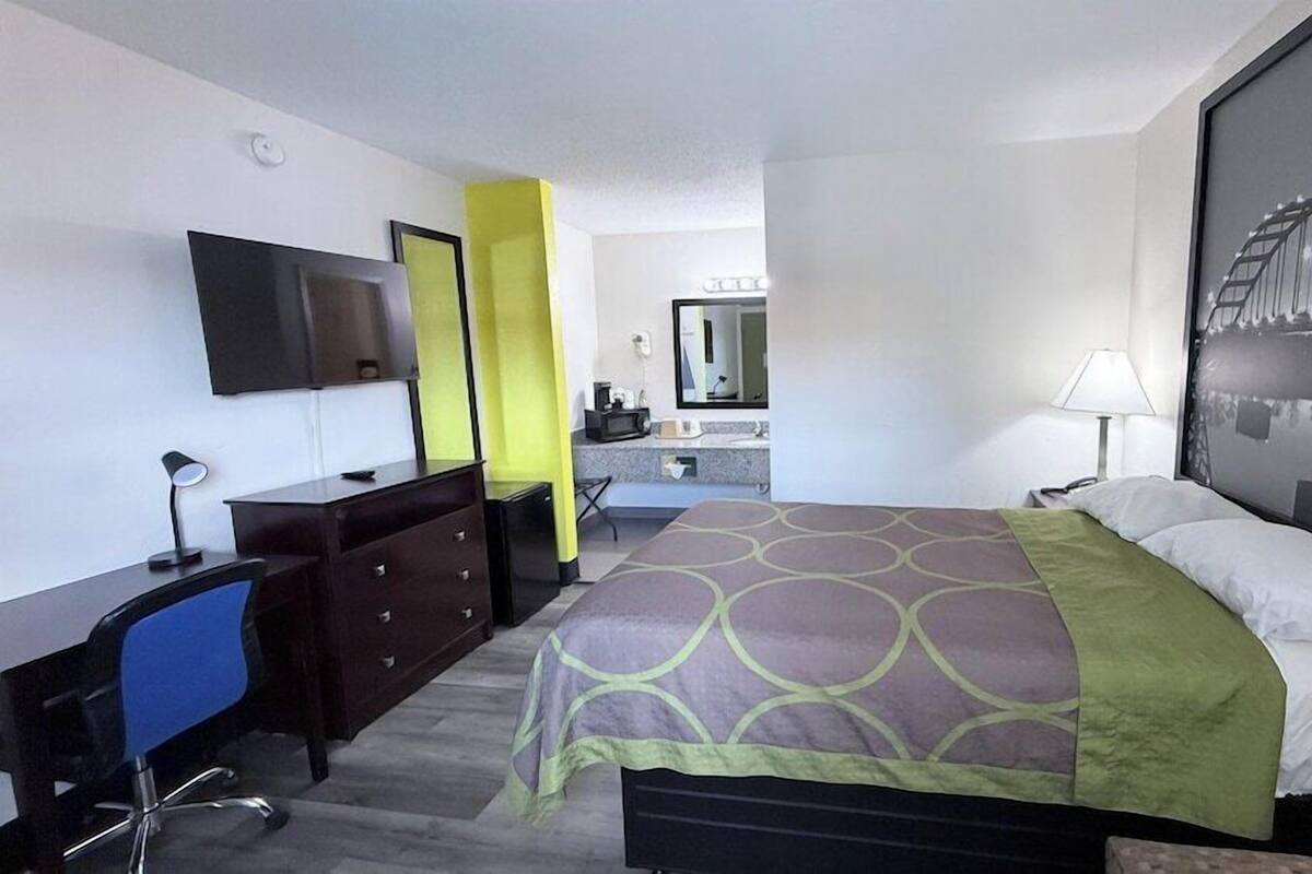 Ein Hotelzimmer mit Bett, Schreibtisch, Stuhl und einem großen Fenster mit Blick auf eine Brücke.
