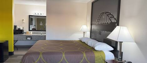A hotel room with a bed, bedside lamps, a telephone, and a large framed picture on the wall.