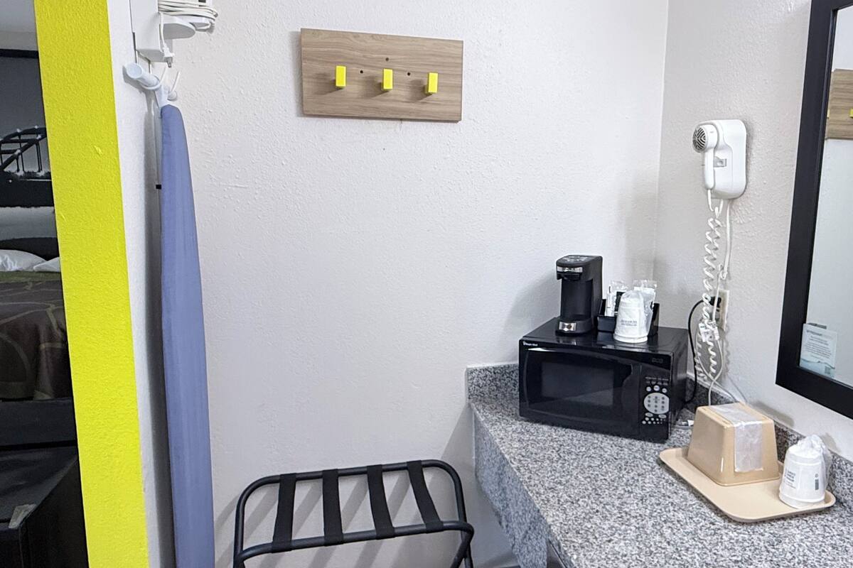 Ein Hotelzimmer mit Mikrowelle, Kaffeemaschine und Telefon auf der Ablagefläche.