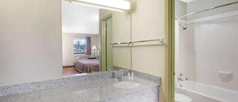 A bathroom with a granite countertop, a sink, a mirror, a shower, and a toilet.