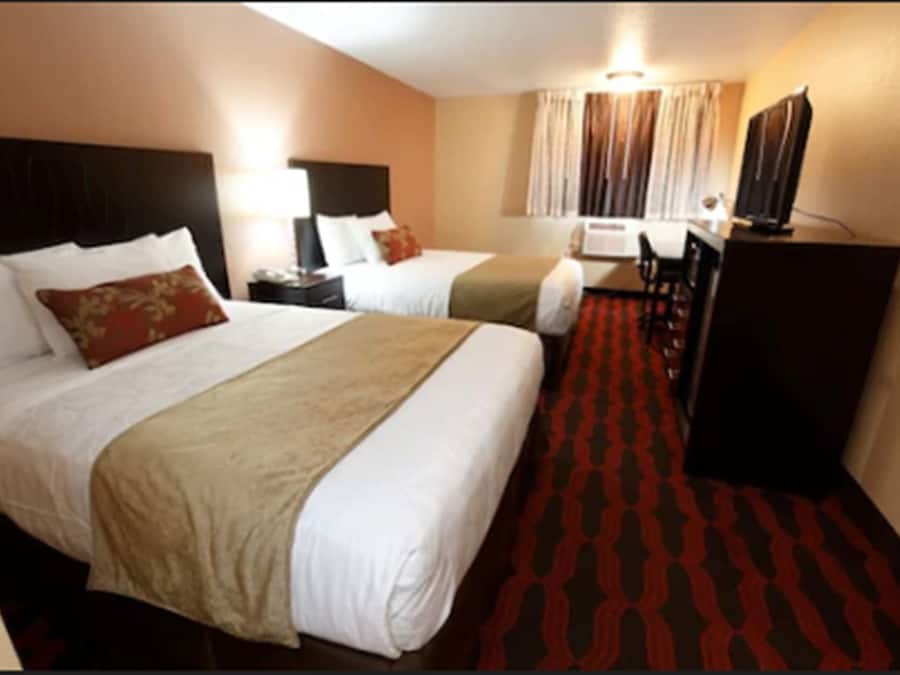 A hotel room with two beds, a desk, and a television.