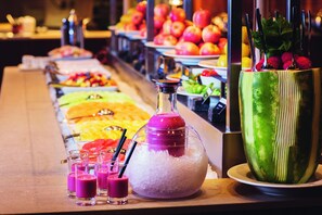 Un bufé con diversos alimentos y una gran sandía como pieza central.