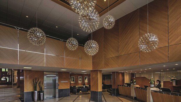 Un hall d’entrée spacieux au design moderne, comprenant un comptoir d’accueil, un espace salon et des luminaires sphériques décoratifs.