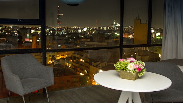 A modern room with a city view, a round table with a flower centerpiece, and two grey chairs. - Hotel El Ejecutivo by Reforma Avenue (Mexico City)