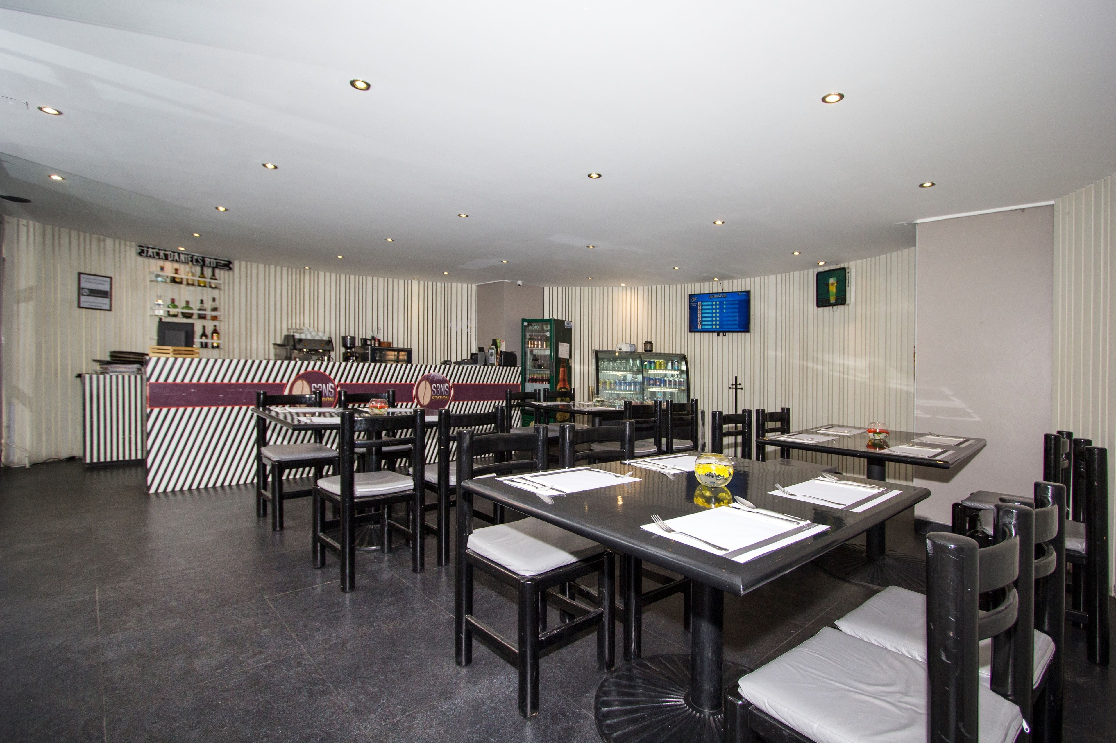 A restaurant with striped walls, a bar area, and multiple dining tables with chairs.