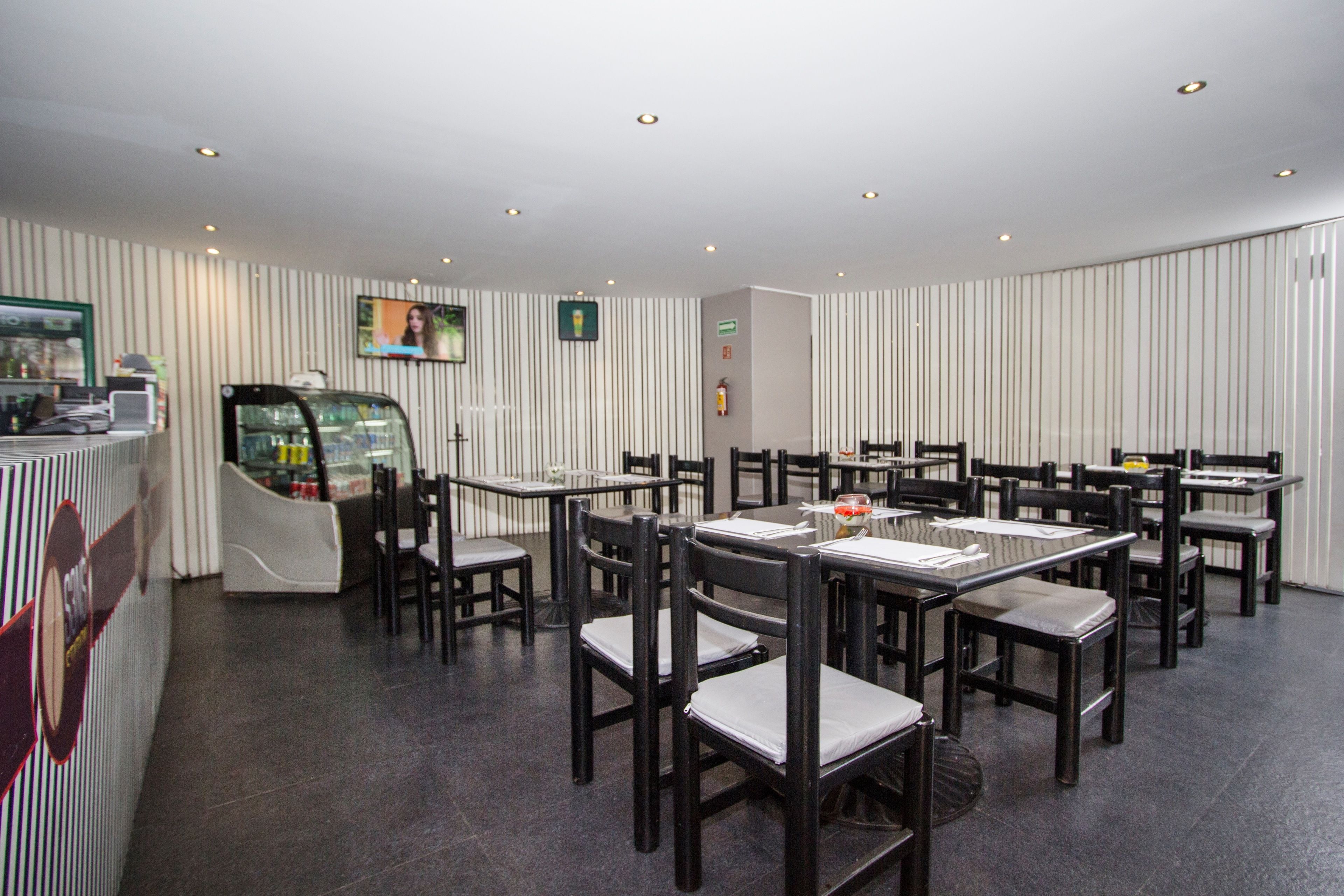 A restaurant with a modern interior, featuring striped wallpaper, dark wooden tables and chairs, and a glass display case.