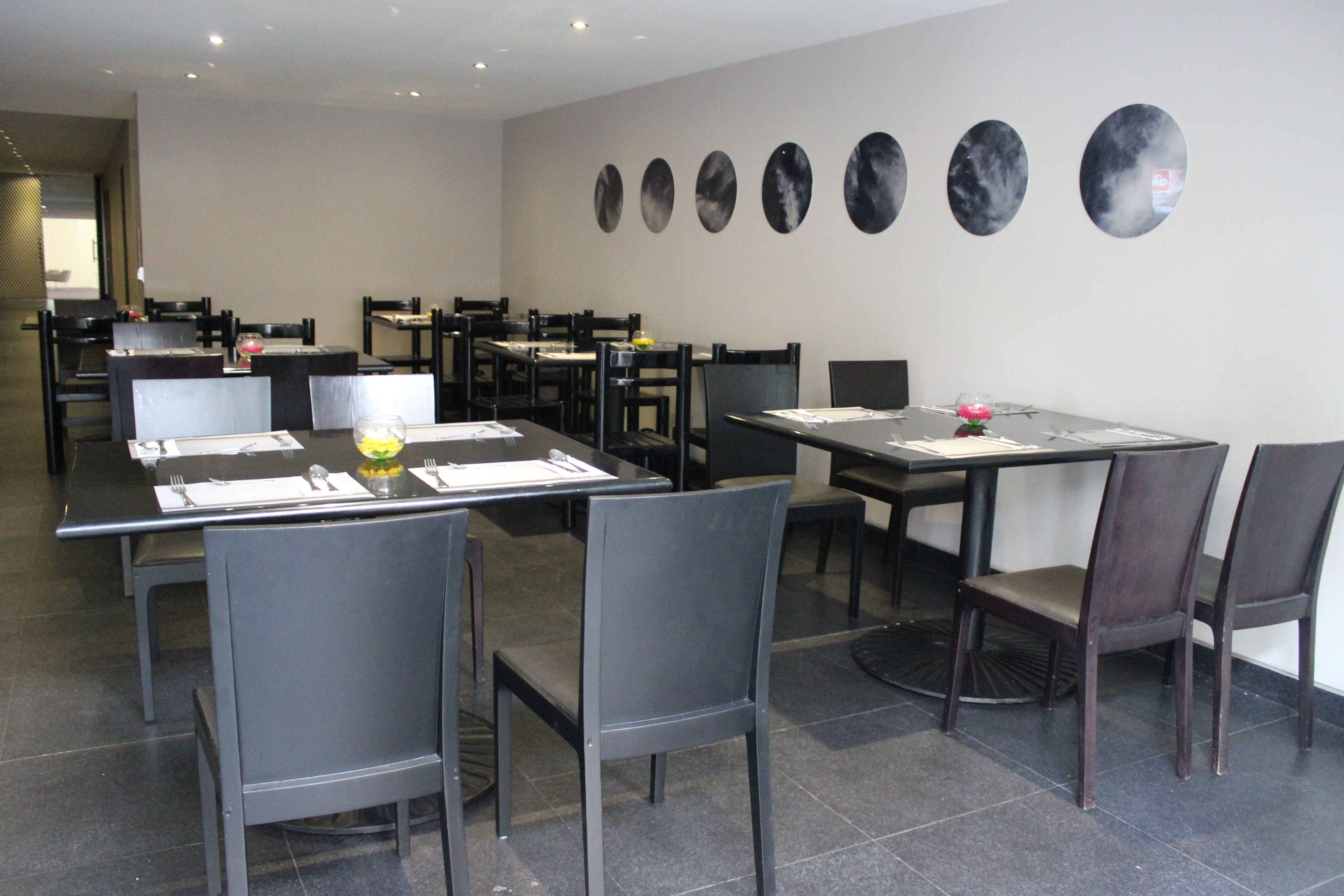 A restaurant with multiple tables and chairs, a tiled floor, and a wall with circular mirrors.