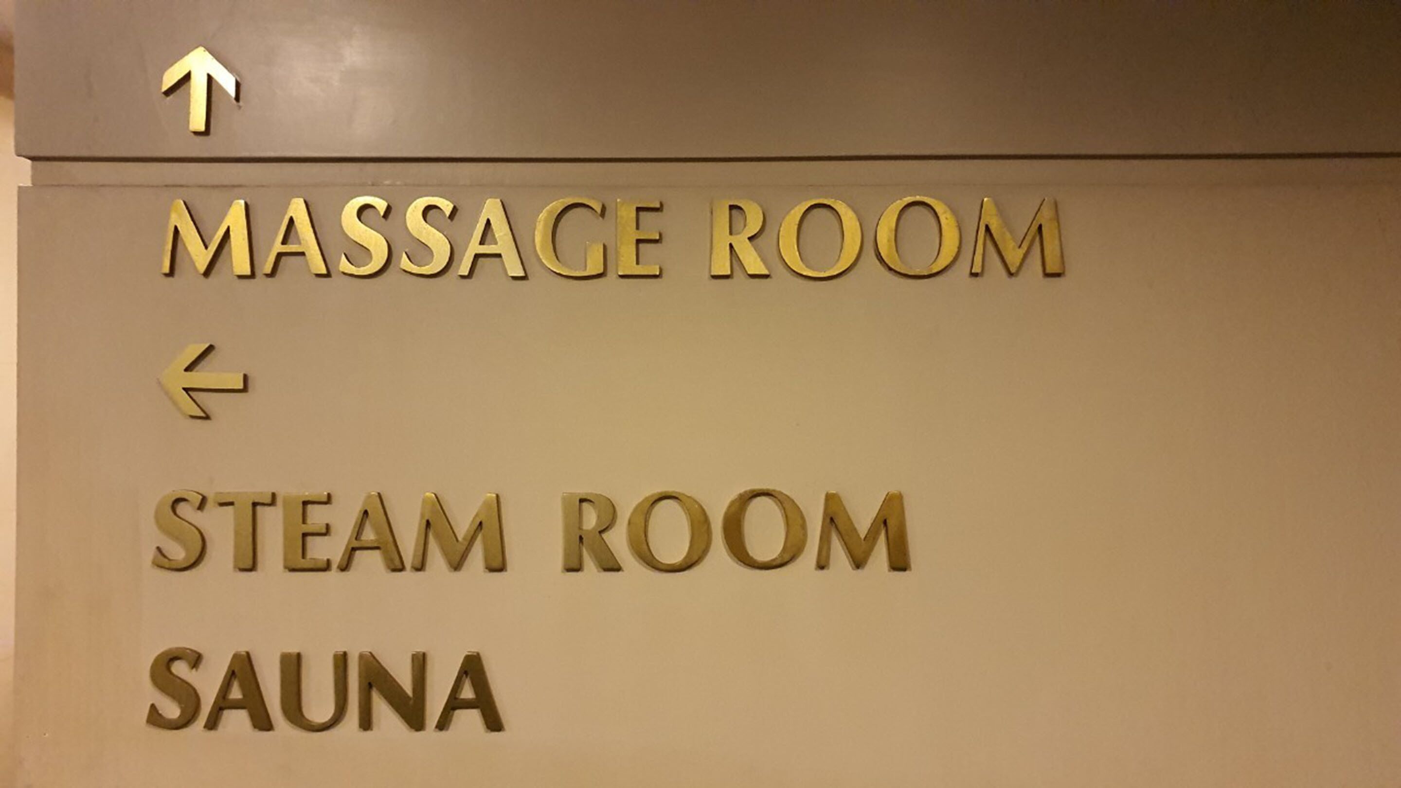 A sign indicating directions to the massage room, steam room, and sauna.