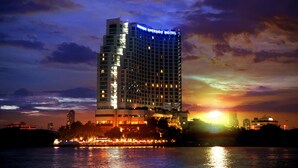 Ein Hochhaus-Hotel mit beleuchteter Beschilderung, Blick auf das Wasser und einem Sonnenuntergangshimmel.