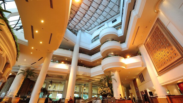 Eine geräumige Lobby mit hohen Decken, mehreren Etagen und einem zentralen Atrium mit Glasdach.