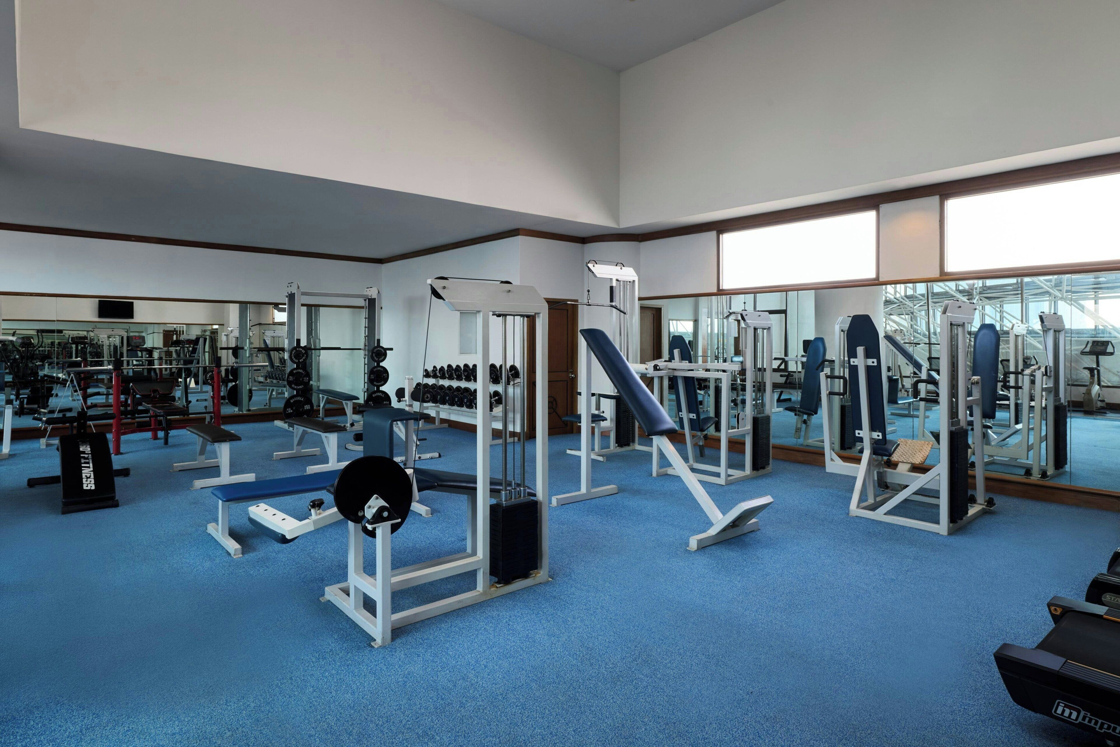 A gym with various exercise equipment, benches, and weight racks.