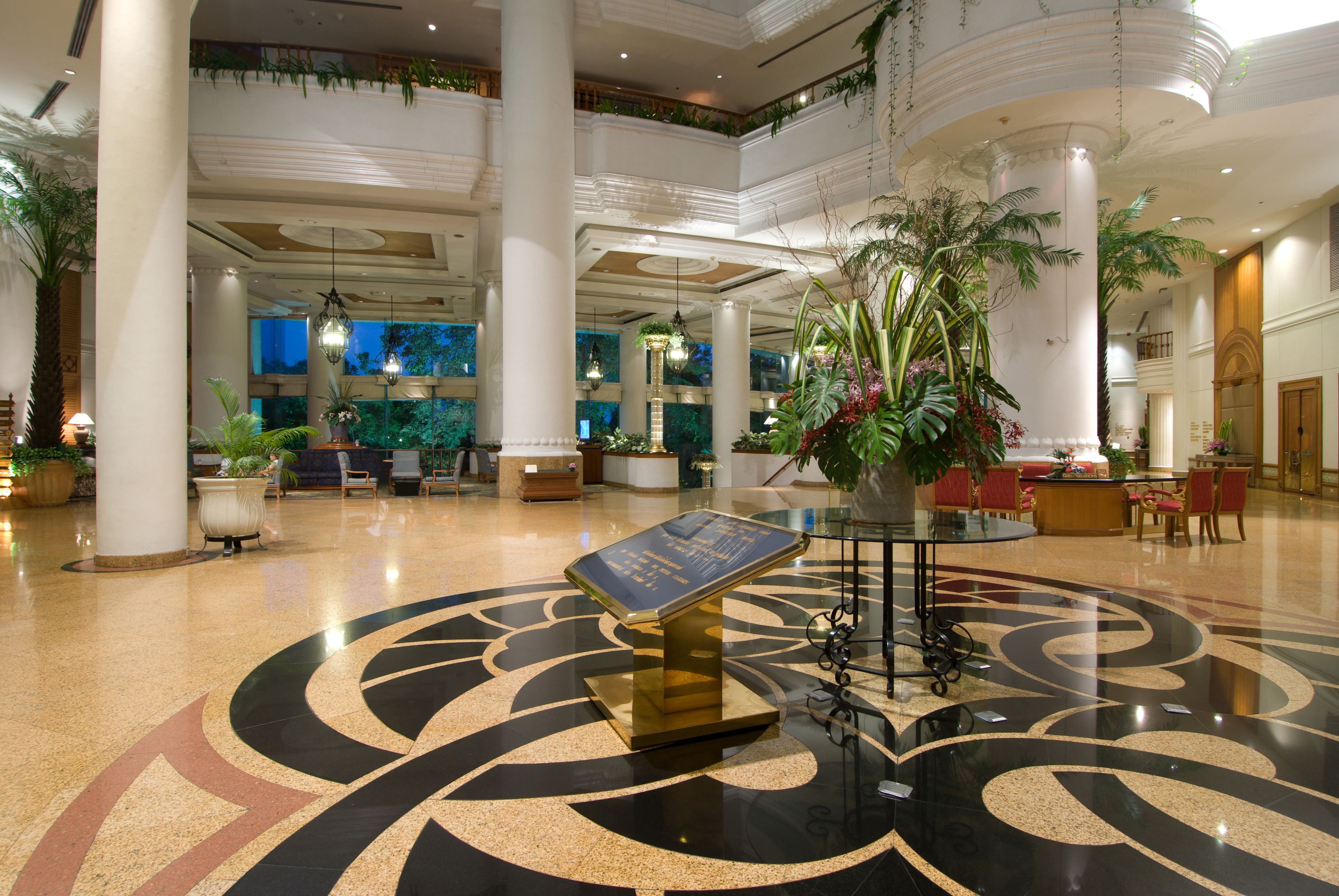 A spacious lobby with a central information desk, multiple seating areas, and large decorative columns.