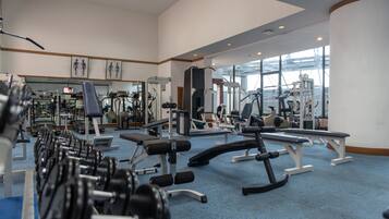 A gym with various exercise equipment, mirrors, and a blue carpeted floor.