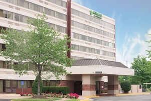 A Wingate hotel with a modern design, featuring a large entrance and a parking area.