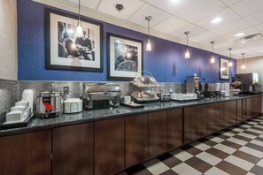 A buffet counter with various food items, coffee machines, and a check-in counter.
