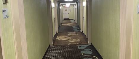 A hotel hallway with a patterned carpet, green walls, and doors numbered 412 and 413.