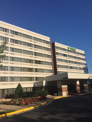 A multi-story hotel with a prominent green logo on the facade.