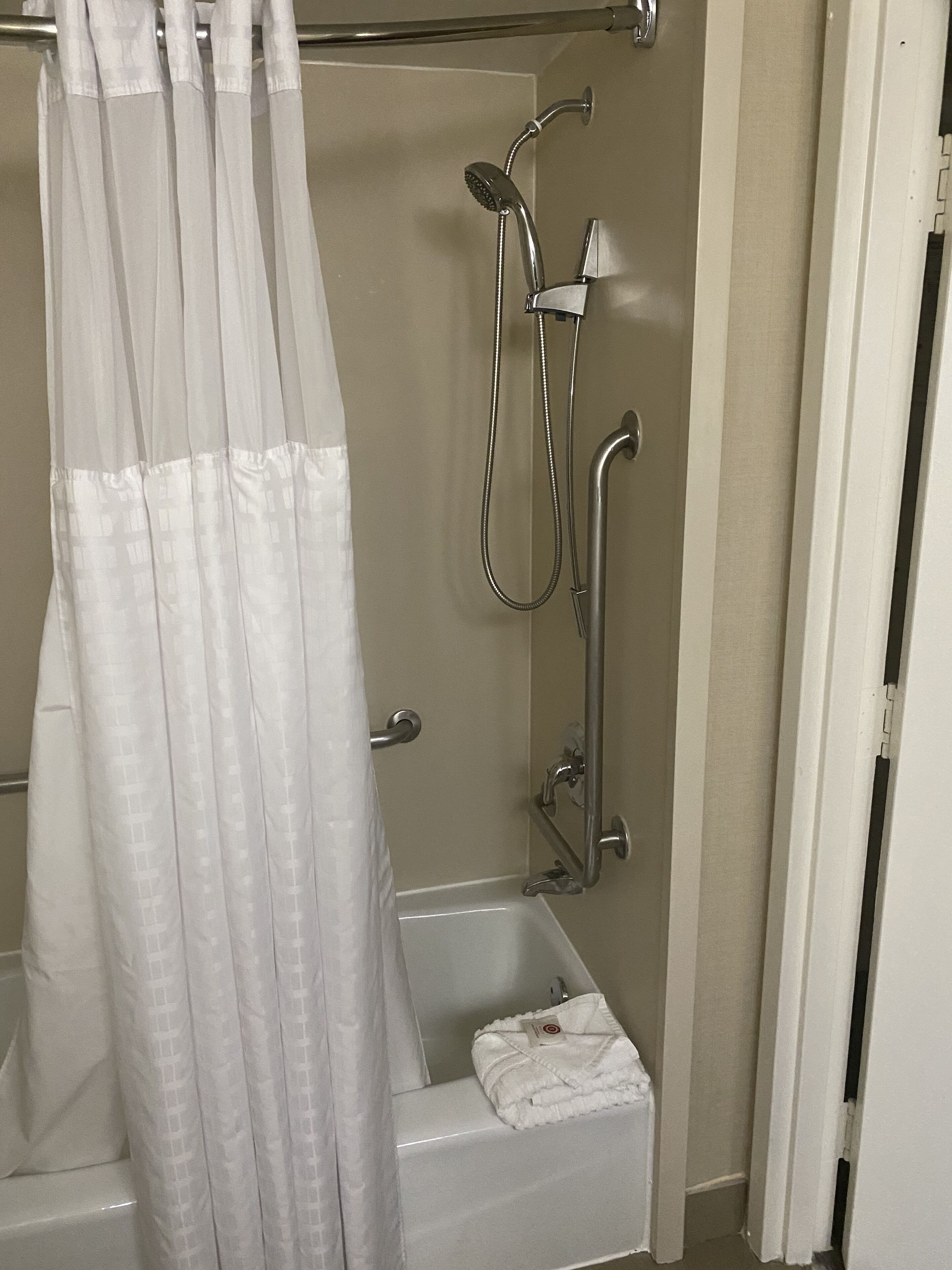 Une salle de bain équipée d’une douche, d’une baignoire et d’une serviette posée sur le bord.