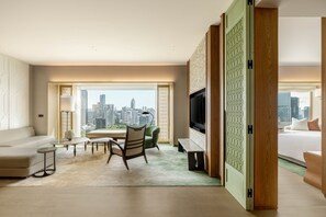 A modern hotel room with a city view, a sofa, a dining table, and a TV. - Dusit Thani Bangkok (Bangkok)