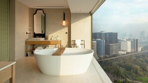 A modern bathroom with a freestanding bathtub, a vanity with a mirror, and a view of a cityscape.