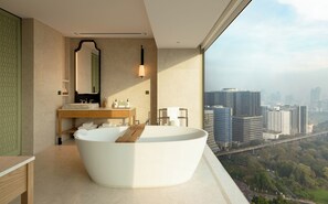 A modern bathroom with a freestanding bathtub, a vanity with a mirror, and a view of a cityscape. - Dusit Thani Bangkok (Bangkok)