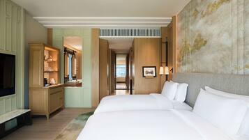 A hotel room with a large bed, a TV, a desk with a mirror, and a view of the city through the window.