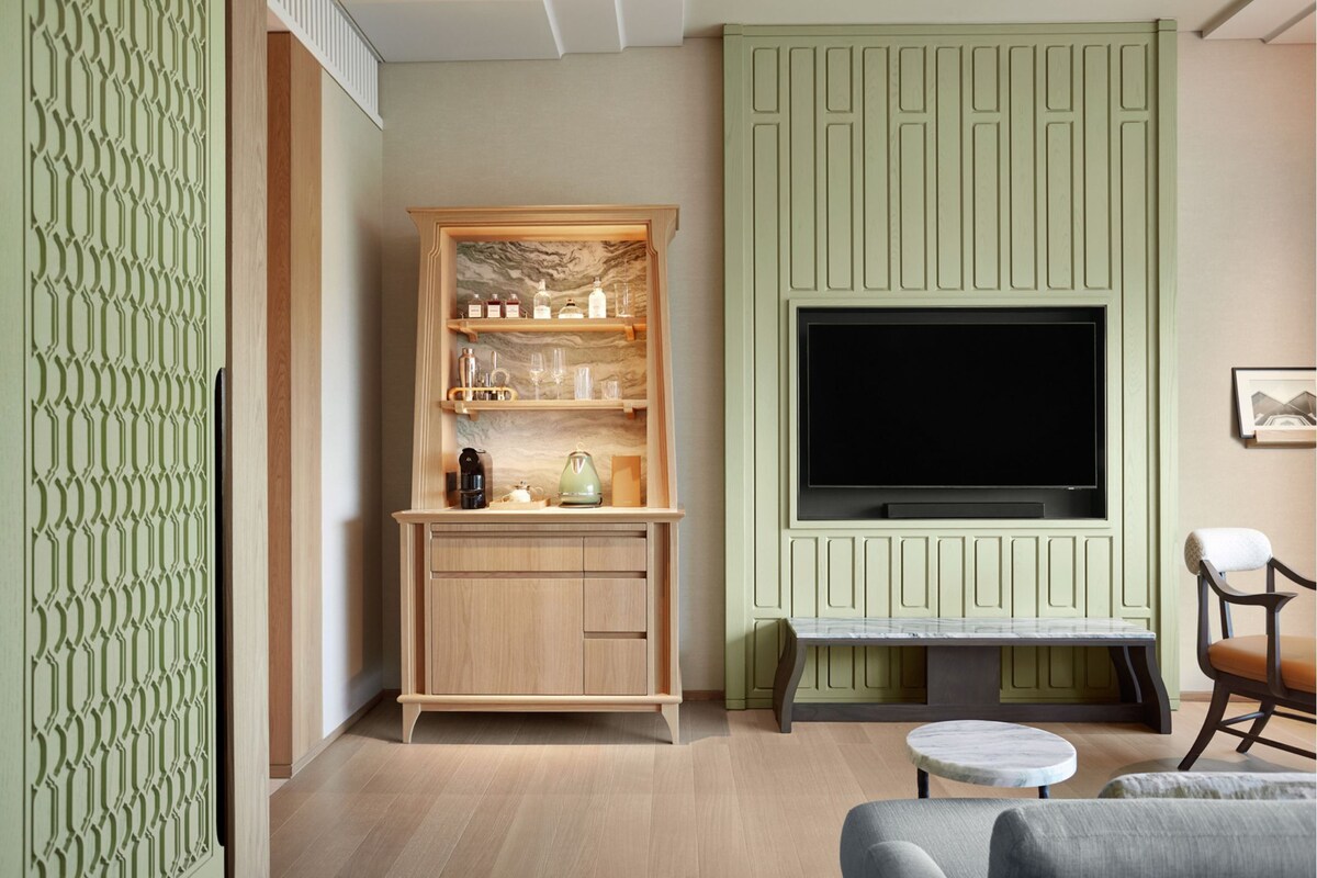 A living room with a wooden cabinet, a television, a bench, and a chair.