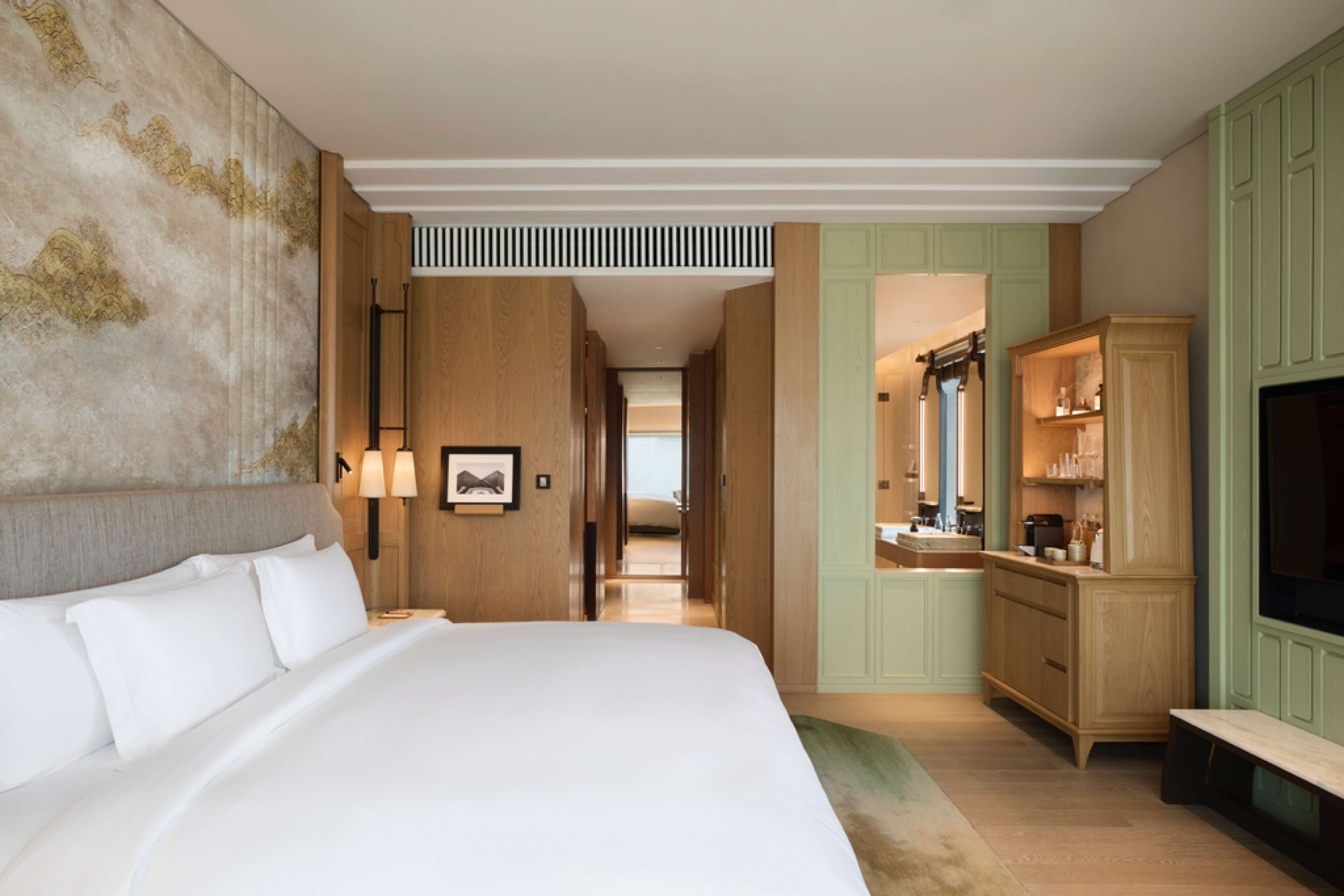 A hotel room with a large bed, a vanity with a mirror, and a television.