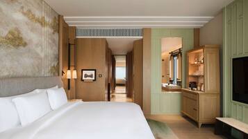 A hotel room with a large bed, a vanity with a mirror, and a television.